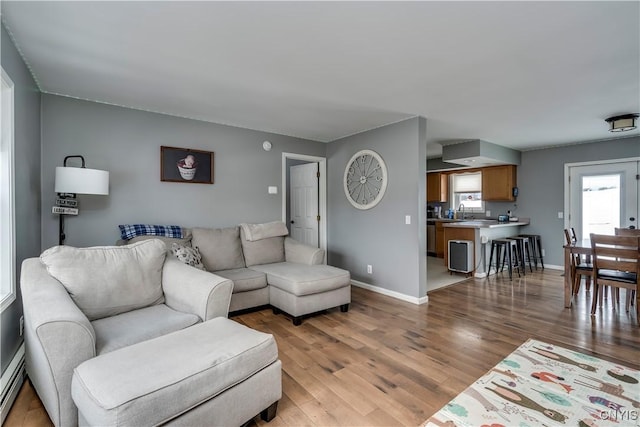 living room featuring light wood-style floors, baseboards, and baseboard heating