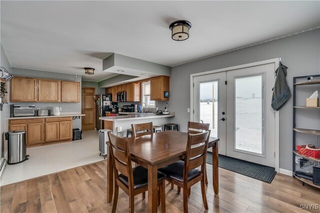 dining area featuring light wood-type flooring, baseboards, and french doors