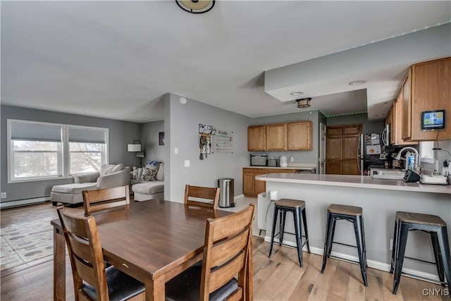 dining area featuring a baseboard heating unit and light wood-style floors