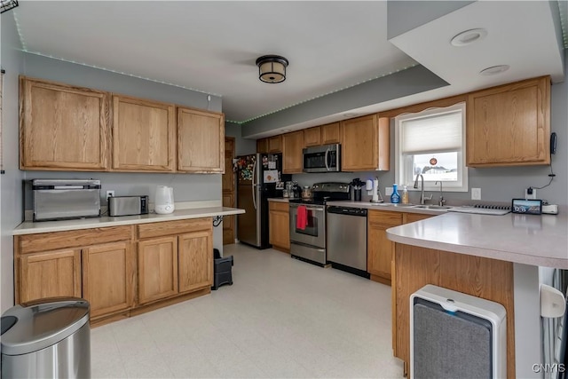 kitchen with a peninsula, appliances with stainless steel finishes, light countertops, and a kitchen breakfast bar