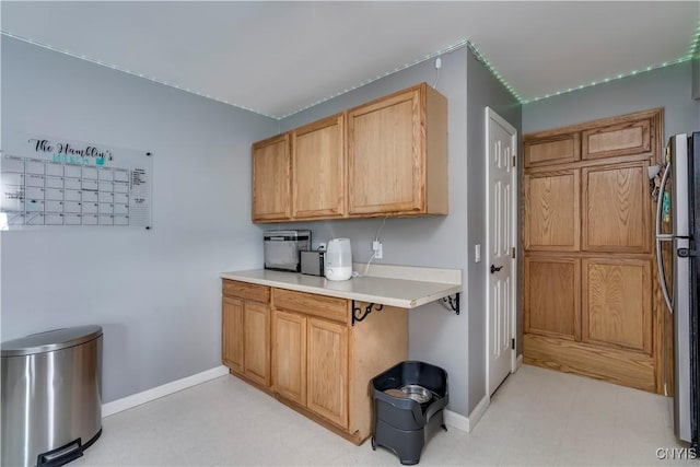 kitchen with light countertops, freestanding refrigerator, and baseboards