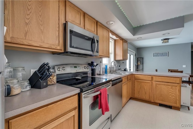 kitchen featuring visible vents, light countertops, appliances with stainless steel finishes, a sink, and a peninsula