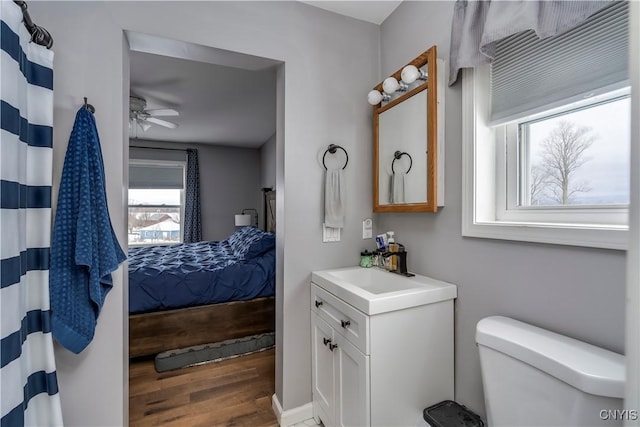 ensuite bathroom with toilet, ensuite bathroom, a ceiling fan, vanity, and wood finished floors