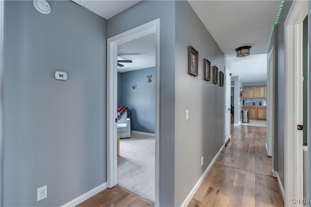 corridor with baseboards and wood finished floors