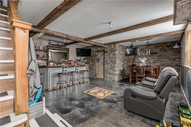 living room featuring a bar, concrete floors, and beam ceiling