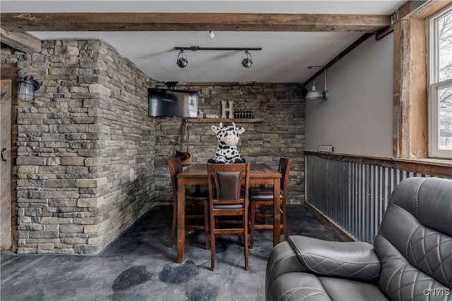 unfurnished dining area with concrete flooring and beamed ceiling