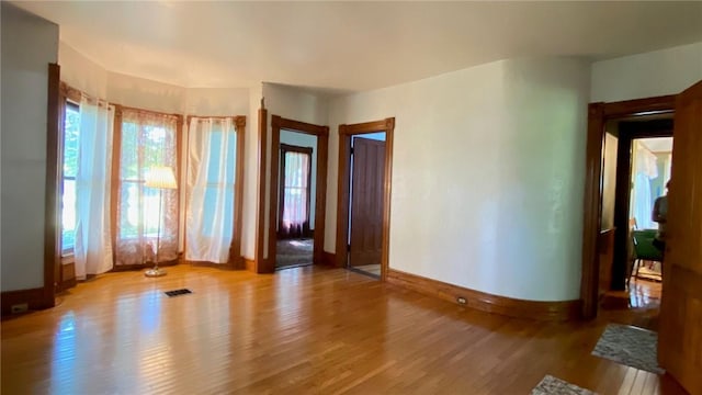 empty room featuring light wood-style floors, visible vents, and baseboards