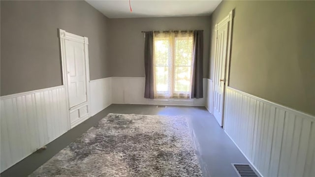 unfurnished room with a wainscoted wall