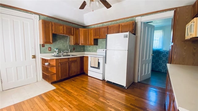 kitchen with white appliances, brown cabinets, a sink, and dark wood-style flooring