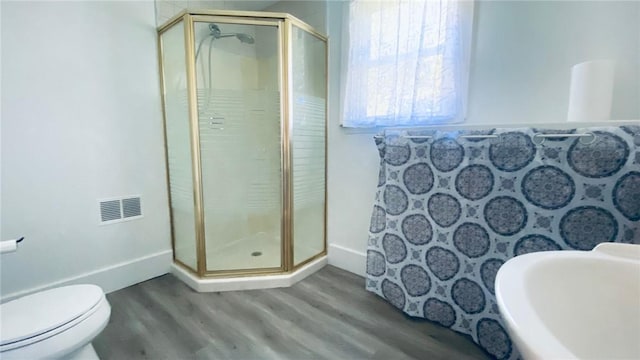 full bathroom featuring a stall shower, visible vents, baseboards, and wood finished floors