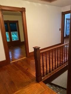 hall with baseboards, an upstairs landing, and wood finished floors