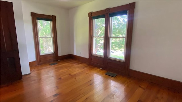 empty room featuring light wood-style floors, visible vents, and baseboards