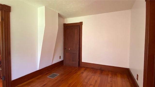 spare room featuring hardwood / wood-style floors, visible vents, and baseboards