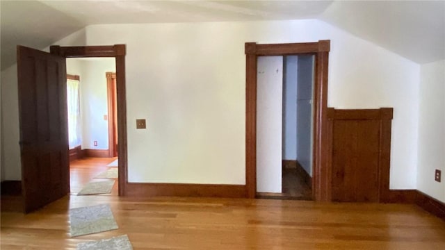 additional living space with vaulted ceiling, light wood-type flooring, and baseboards