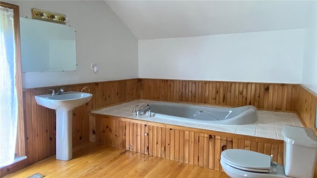 bathroom featuring wood walls, vaulted ceiling, and wainscoting