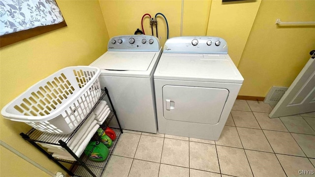 laundry area featuring light tile patterned floors, laundry area, washer and dryer, and baseboards