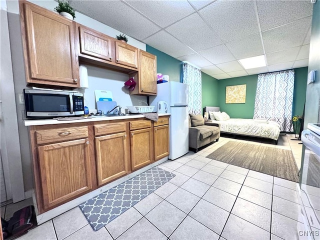 kitchen featuring stainless steel microwave, open floor plan, freestanding refrigerator, light tile patterned flooring, and light countertops