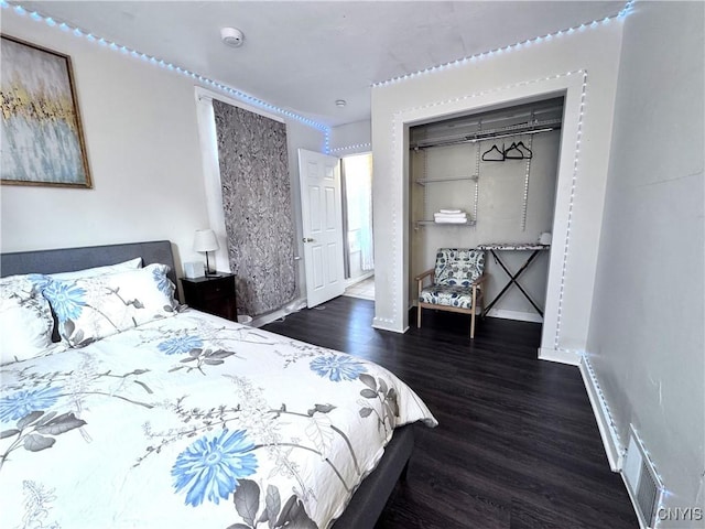 bedroom with a closet, baseboards, visible vents, and wood finished floors