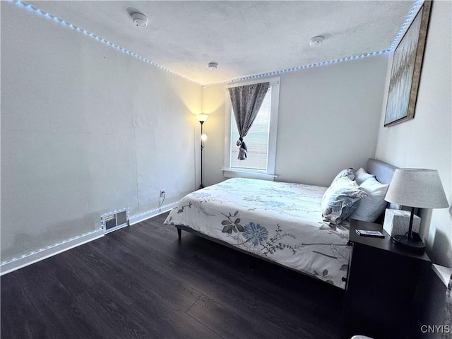 bedroom featuring visible vents, baseboards, and wood finished floors