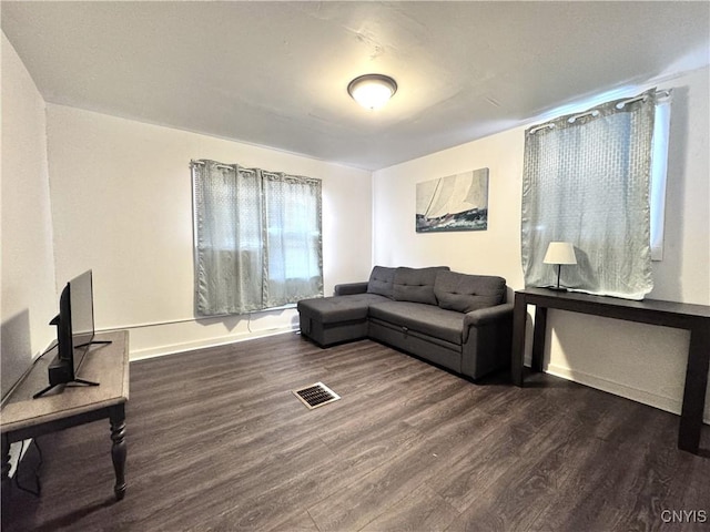 living room with visible vents, baseboards, and wood finished floors