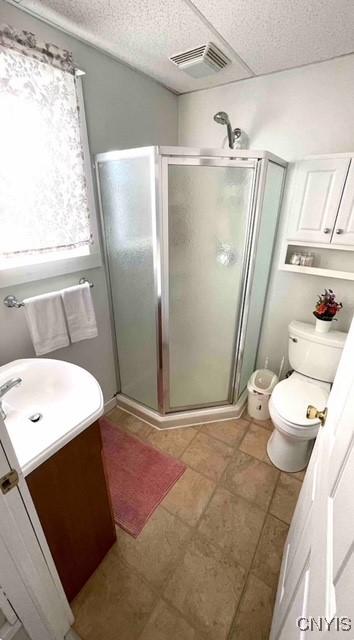 full bath featuring vanity, toilet, visible vents, and a stall shower