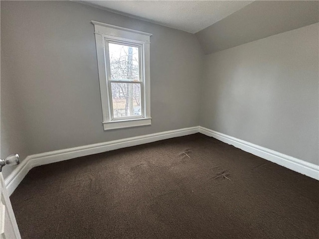 additional living space featuring lofted ceiling, a textured ceiling, dark carpet, and baseboards