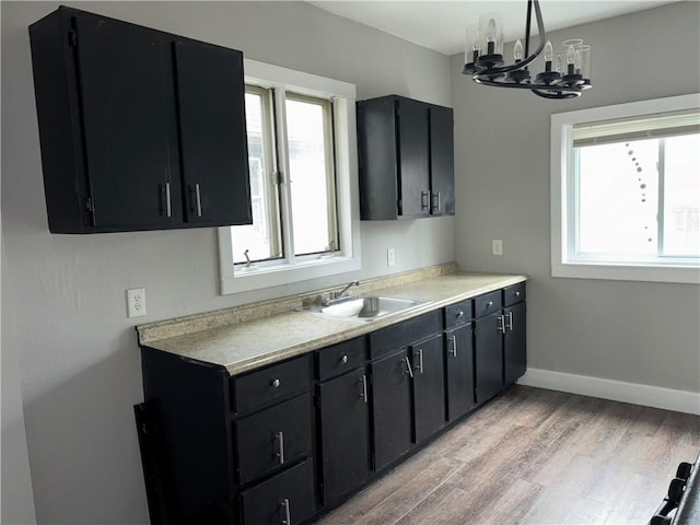 kitchen featuring dark cabinets, a wealth of natural light, light countertops, and a sink