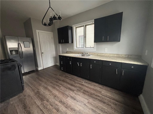 kitchen featuring stainless steel refrigerator with ice dispenser, light countertops, dark wood-type flooring, a sink, and dark cabinets