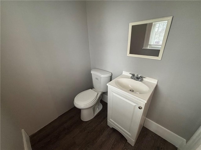 bathroom featuring toilet, baseboards, wood finished floors, and vanity