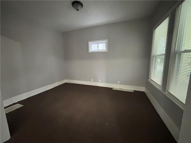 unfurnished room featuring dark colored carpet and baseboards