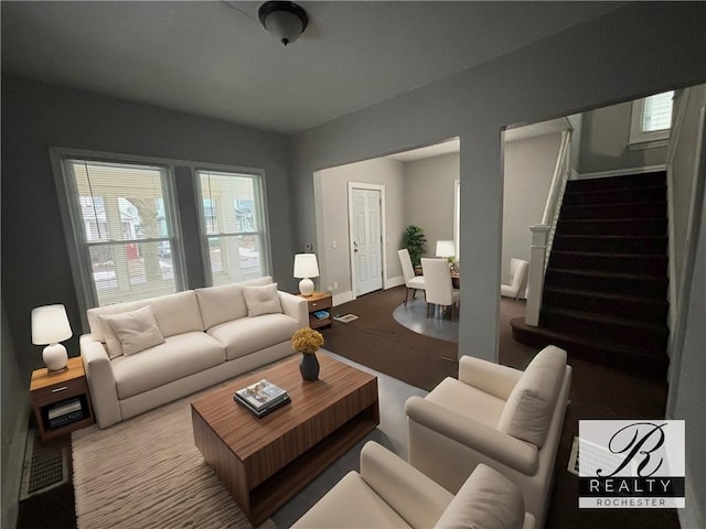 living room with plenty of natural light, baseboards, and stairs