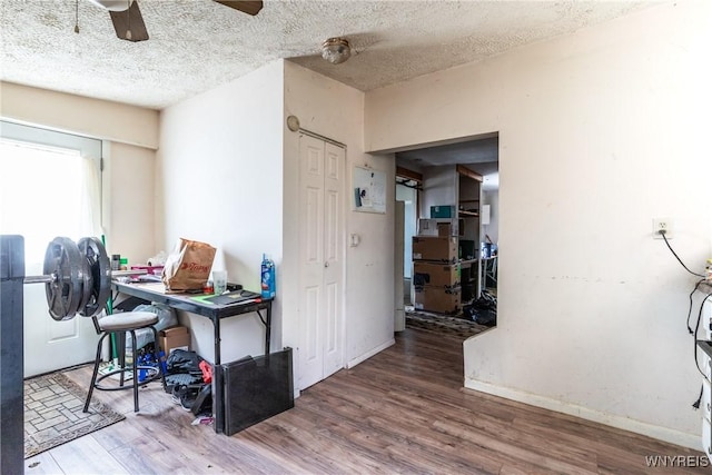 interior space featuring a textured ceiling, a ceiling fan, and wood finished floors