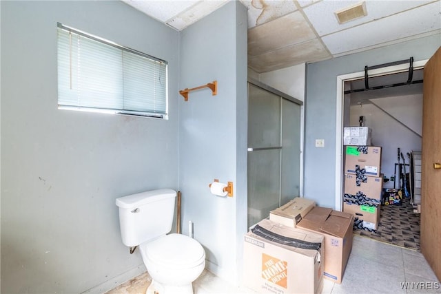 bathroom with toilet, a shower with door, visible vents, and a paneled ceiling