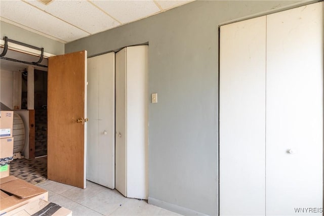 unfurnished bedroom with a drop ceiling and light tile patterned floors