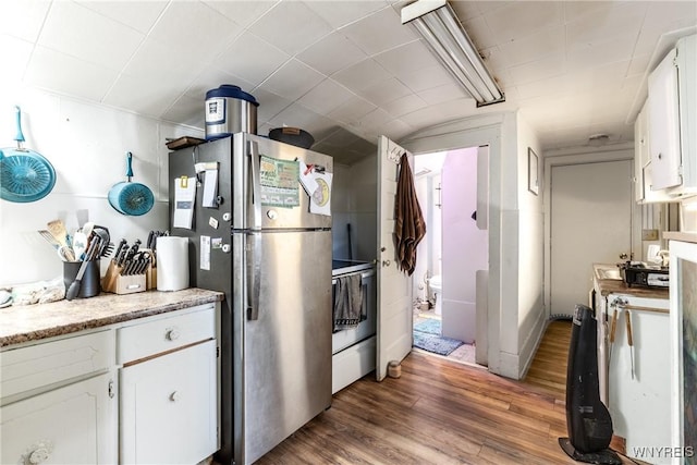 kitchen featuring white cabinetry, wood finished floors, electric stove, and freestanding refrigerator