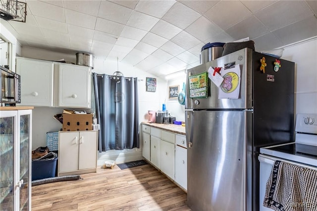 kitchen featuring lofted ceiling, electric range, white cabinets, freestanding refrigerator, and light wood finished floors