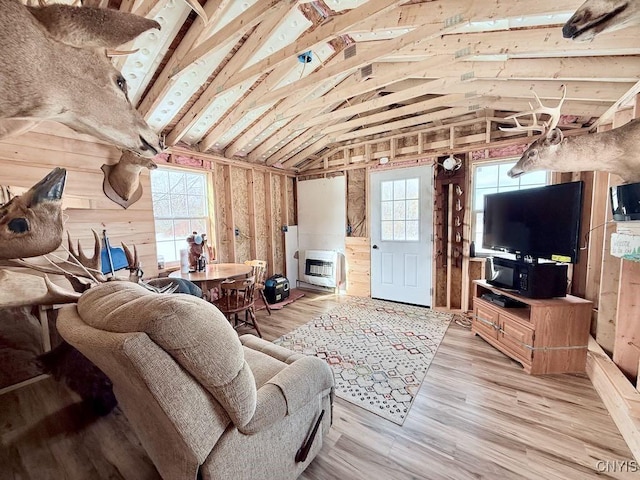 living room featuring light wood-type flooring, vaulted ceiling, and heating unit