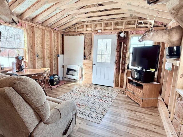 living area with vaulted ceiling, light wood-type flooring, and heating unit