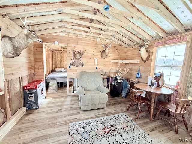 living area featuring lofted ceiling, wooden walls, and wood finished floors