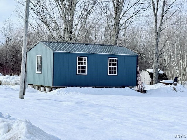 snow covered structure with an outbuilding