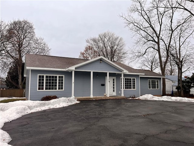 ranch-style home with a shingled roof and fence