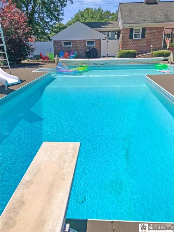 view of pool with a fenced in pool, a patio, fence, a water slide, and a diving board