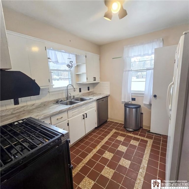 kitchen with decorative backsplash, freestanding refrigerator, a sink, stainless steel dishwasher, and gas stove