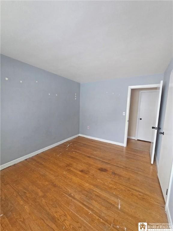 unfurnished room with baseboards and wood finished floors