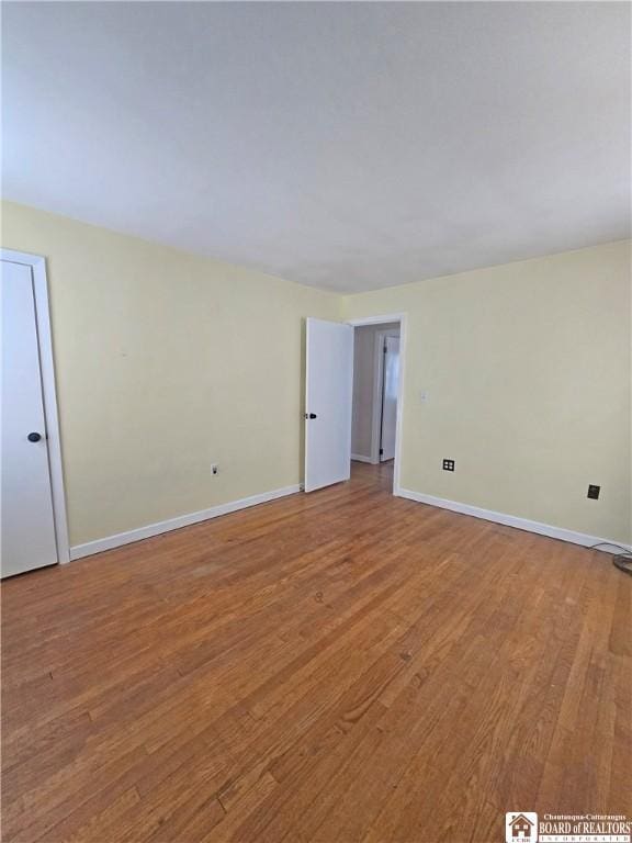 spare room featuring baseboards and wood finished floors