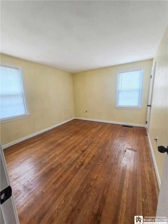 spare room with baseboards, visible vents, and hardwood / wood-style floors