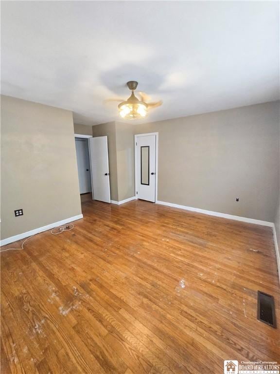 spare room featuring light wood finished floors, visible vents, and baseboards