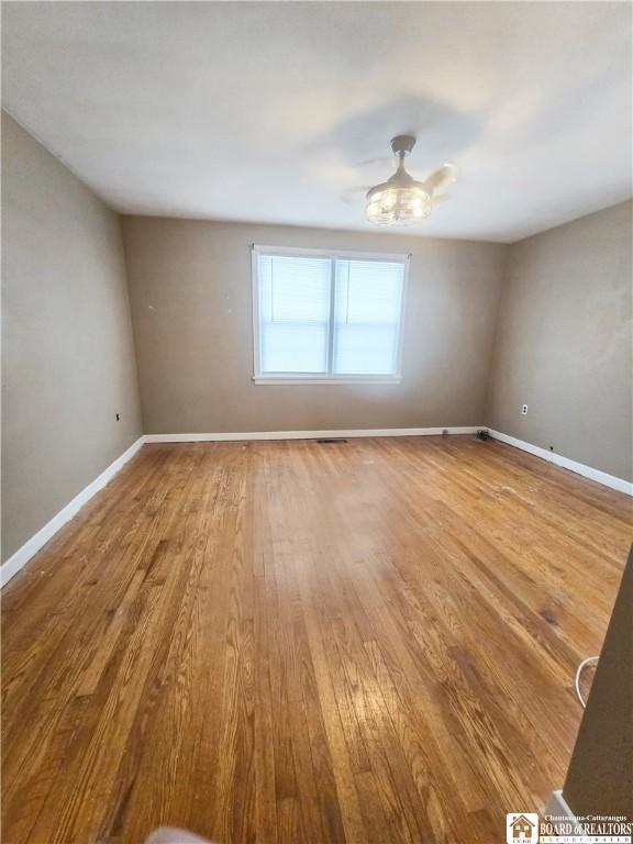 spare room featuring a ceiling fan, baseboards, and wood finished floors