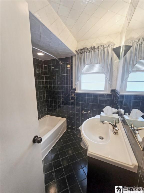 bathroom featuring tile patterned flooring, shower / washtub combination, tile walls, and vanity