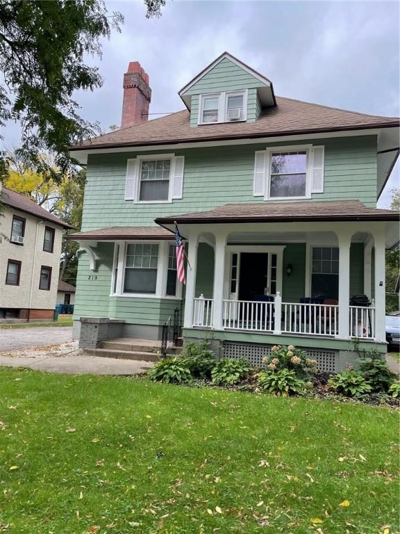 american foursquare style home with covered porch and a front yard